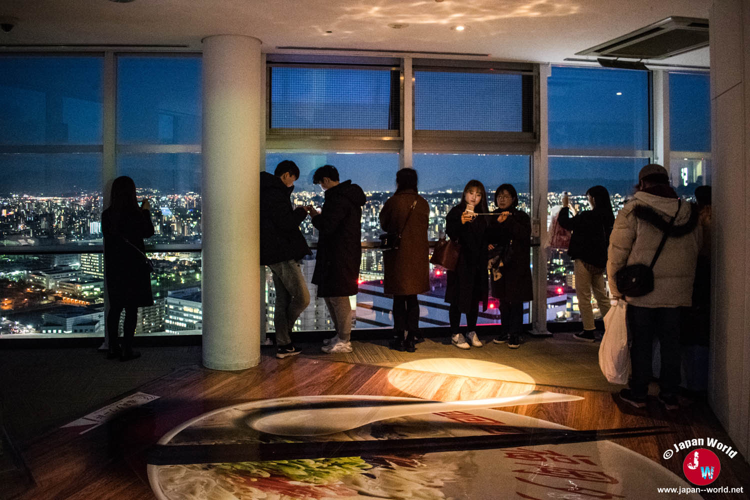 Visiteurs devant les baies vitrées de l'observatoire de la Fukuoka Tower